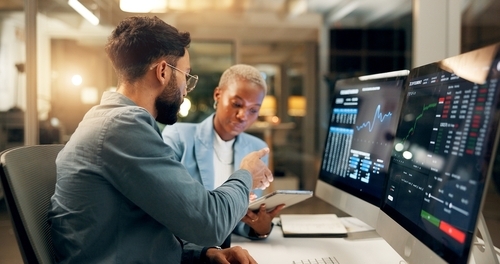 Two people working at computers on investments