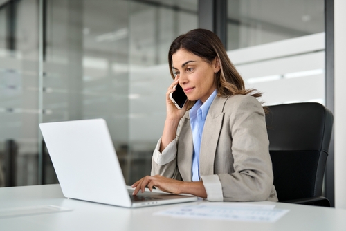 Woman on the phone sitting behind a laptop